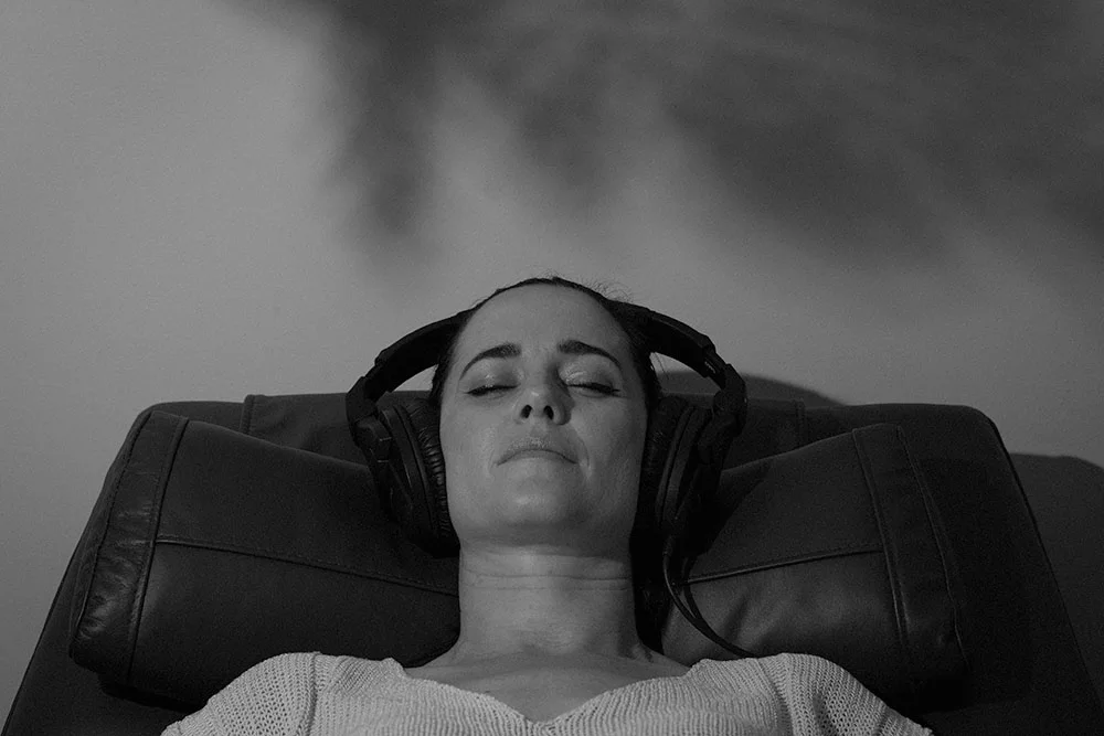 Woman with eyes closed and headphones on receiving sound healing
